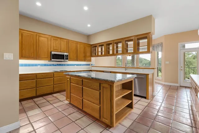 a kitchen with stainless steel appliances granite countertop a stove a sink and a microwave
