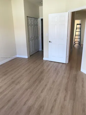 an empty room with wooden floor and hallway