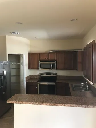 a kitchen with granite countertop a refrigerator and a sink
