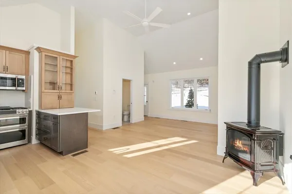 a view of an empty room with kitchen and window