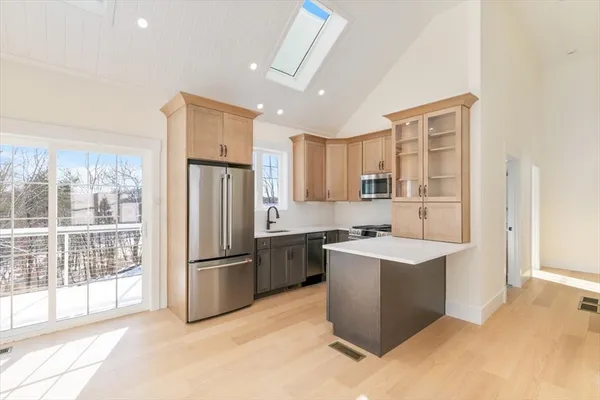 a kitchen with stainless steel appliances granite countertop a refrigerator a sink dishwasher a stove with white cabinets and wooden floor