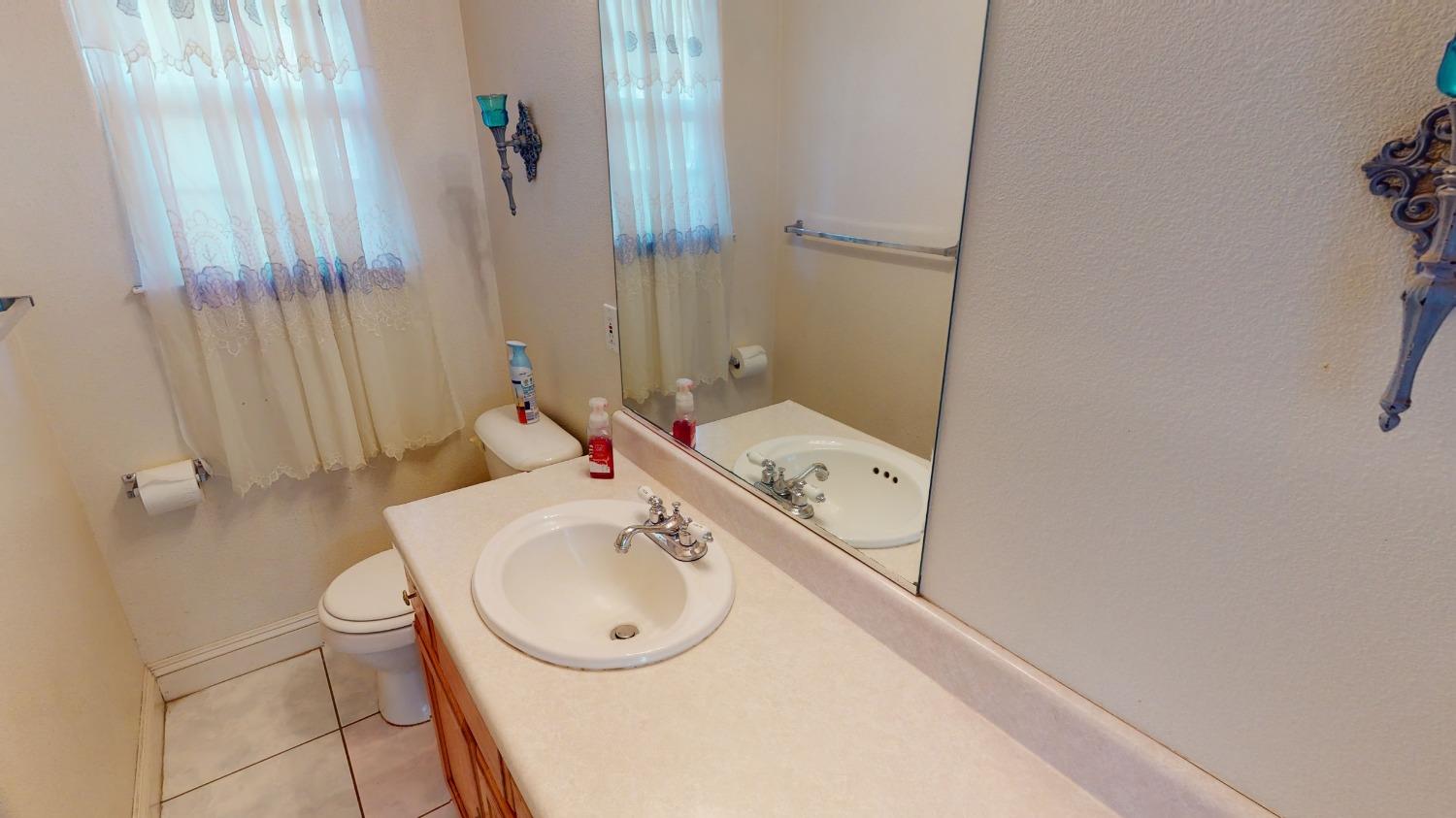 926 North Frankwood Avenue Reedley, CA 93654 - Photo 17 of 32 a bathroom with a sink and mirror with toilet