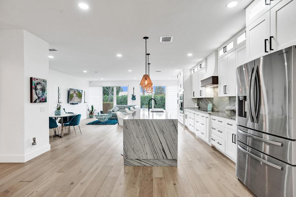 6800 Via Regina Boca Raton, FL 33433 - Photo 5 of 58 a kitchen with stainless steel appliances granite countertop a refrigerator oven a sink dishwasher and white cabinets with wooden floor