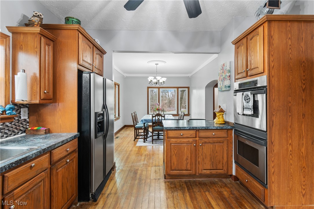 6349 Manchester Road Clinton, OH 44216 - Photo 6 of 23 Kitchen featuring appliances with stainless steel finishes, dark hardwood / wood-style flooring, decorative backsplash, hanging light fixtures, and kitchen peninsula
