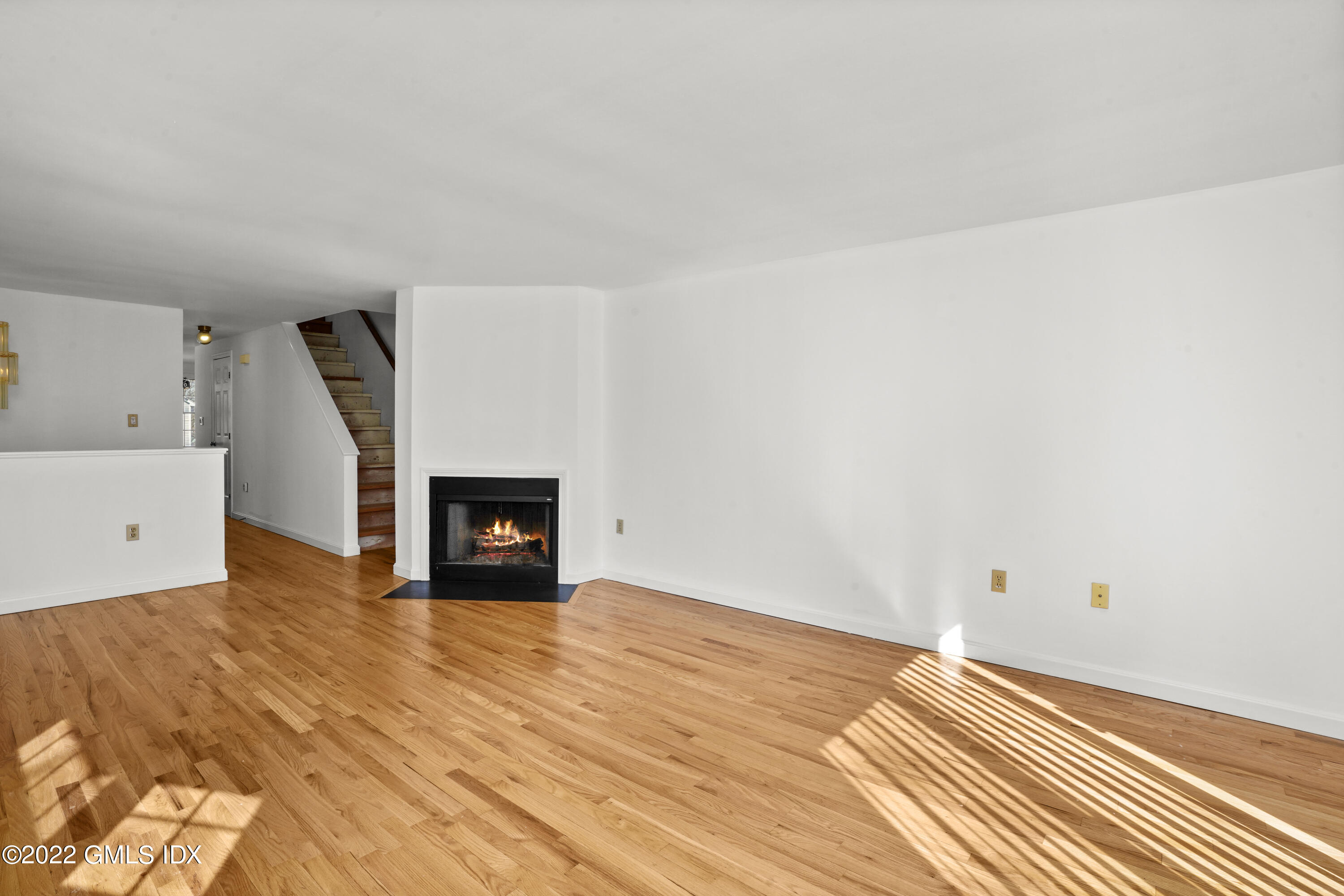 39 Alexander Street, Unit B Greenwich, CT 06830 - Photo 3 of 17 a view of an empty room with wooden floor and a fireplace