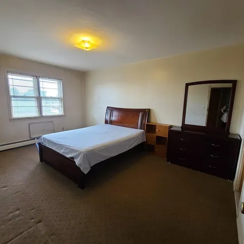 a bedroom with a bed and a dresser next to a window