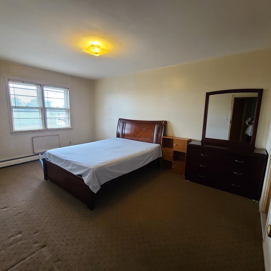 85-10 165th Street Queens, NY 11432 - Photo 11 of 24 a bedroom with a bed and a dresser next to a window