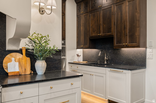 4871 South Homestead Way Washington, UT 84780 - Photo 27 of 151 Kitchen featuring backsplash, dark stone countertops, light wood-type flooring, pendant lighting, and dark wood finish cabinetry