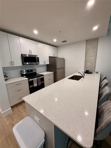 a kitchen with kitchen island a white counter top space cabinets and stainless steel appliances