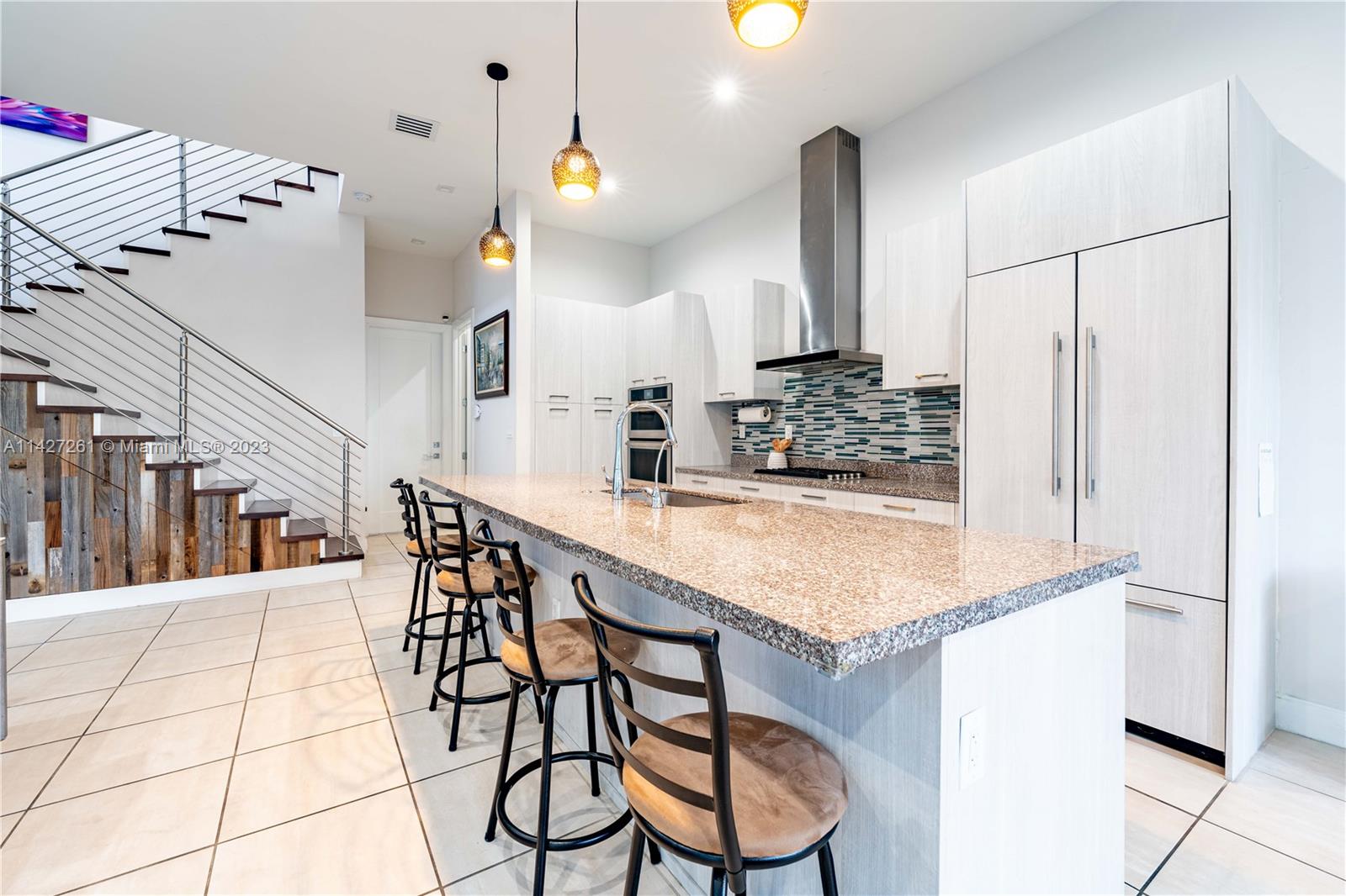 8210 Northwest 46th Street Doral, FL 33166 - Photo 13 of 59 a kitchen with stainless steel appliances kitchen island granite countertop a table chairs in it and wooden floors