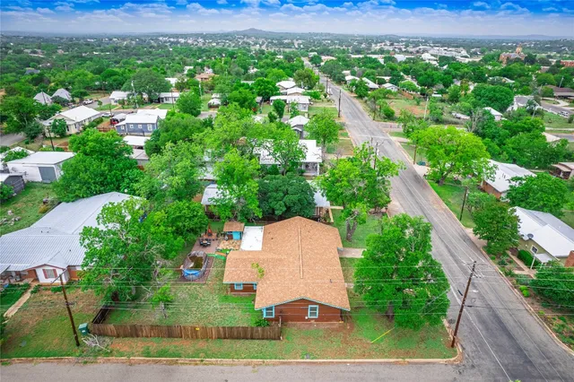 an aerial view of residential houses with outdoor space and trees