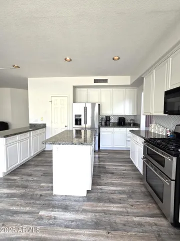 a large kitchen with cabinets wooden floor and stainless steel appliances