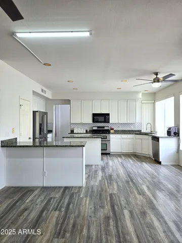 a kitchen with granite countertop a refrigerator and a stove top oven