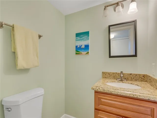 a bathroom with a granite countertop sink a toilet and mirror
