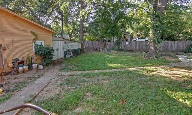 a view of a backyard with large trees and wooden fence