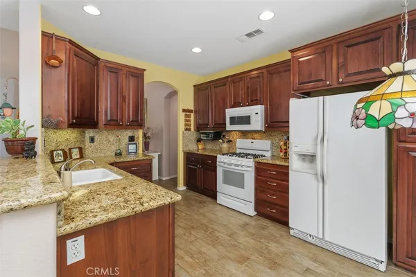 a kitchen with stainless steel appliances granite countertop a refrigerator stove top oven and sink