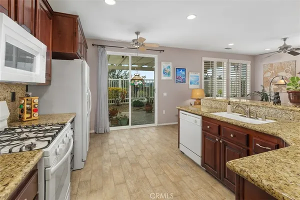 a kitchen with stainless steel appliances granite countertop a stove a sink dishwasher and a refrigerator with wooden floor