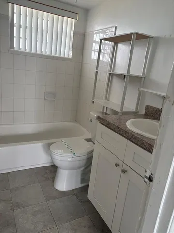 a bathroom with a granite countertop sink a toilet and bathtub