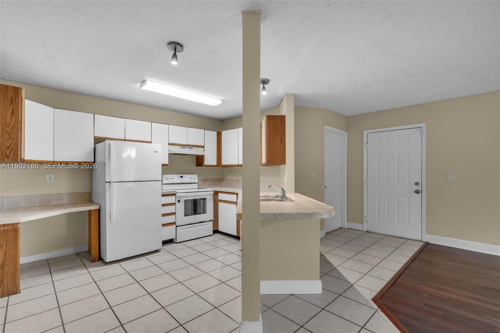 4035 West McNab Road, Unit F101 Pompano Beach, FL 33069 - Photo 9 of 25 a kitchen with a refrigerator and white cabinets