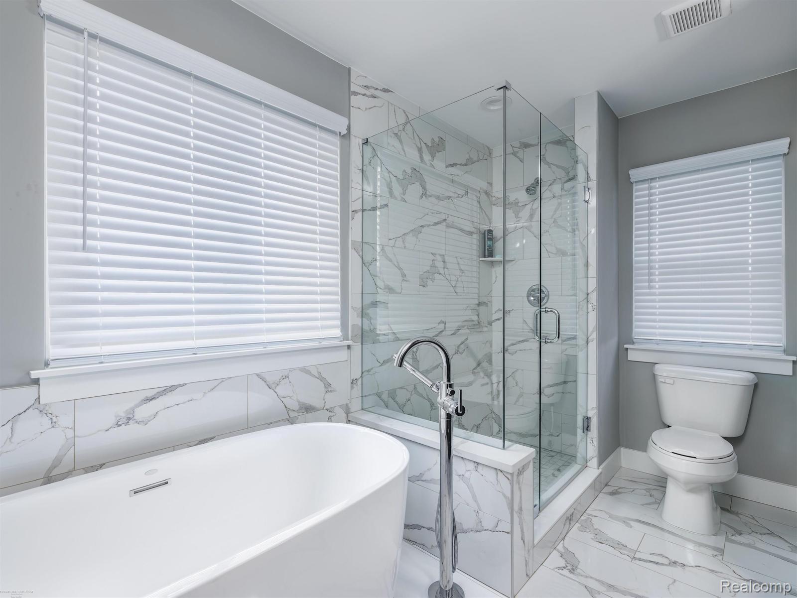 47705 Card Road Macomb, MI 48044 - Photo 24 of 53 Modern bathroom featuring a freestanding soaking tub with a floor-mounted faucet, a glass-enclosed shower, and a white toilet