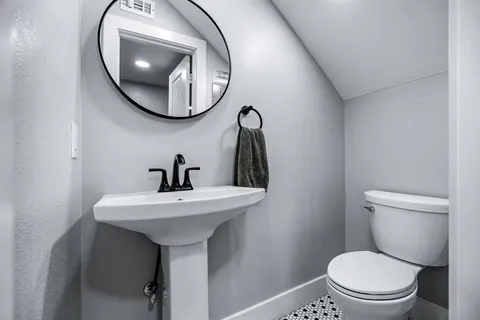 a bathroom with a toilet a sink and mirror