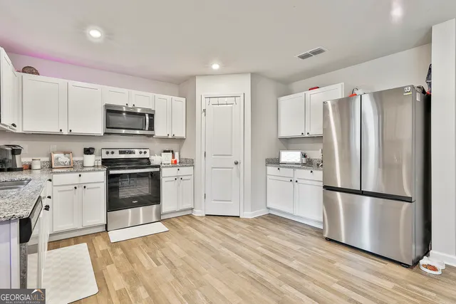 a kitchen with white cabinets stainless steel appliances and wooden floor