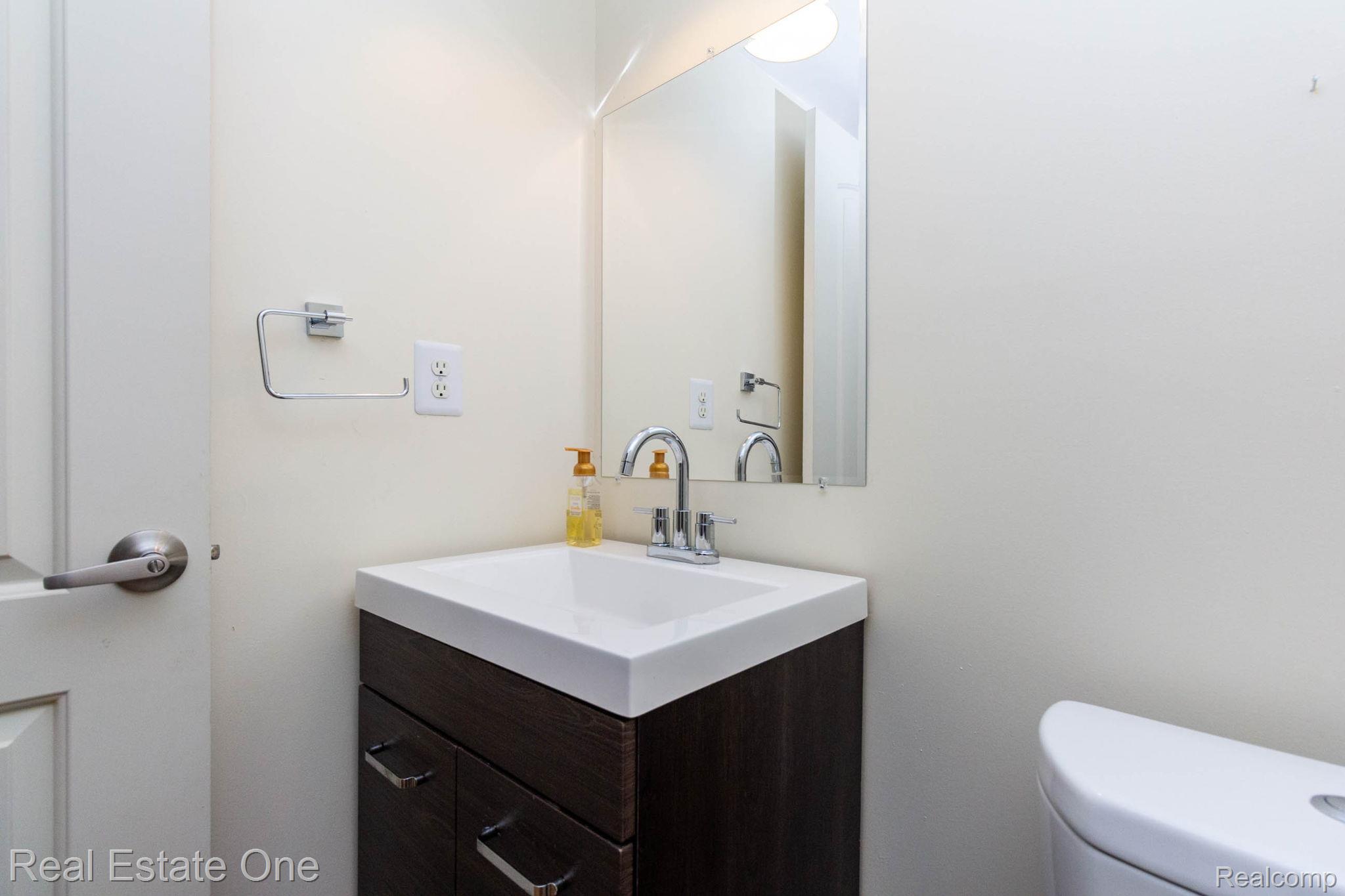 111 Manor Way Rochester, MI 48309 - Photo 25 of 36 White rectangular sink with a chrome faucet, set into a dark wood-finish vanity with chrome pulls