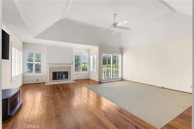 a view of an empty room with wooden floor and a fireplace