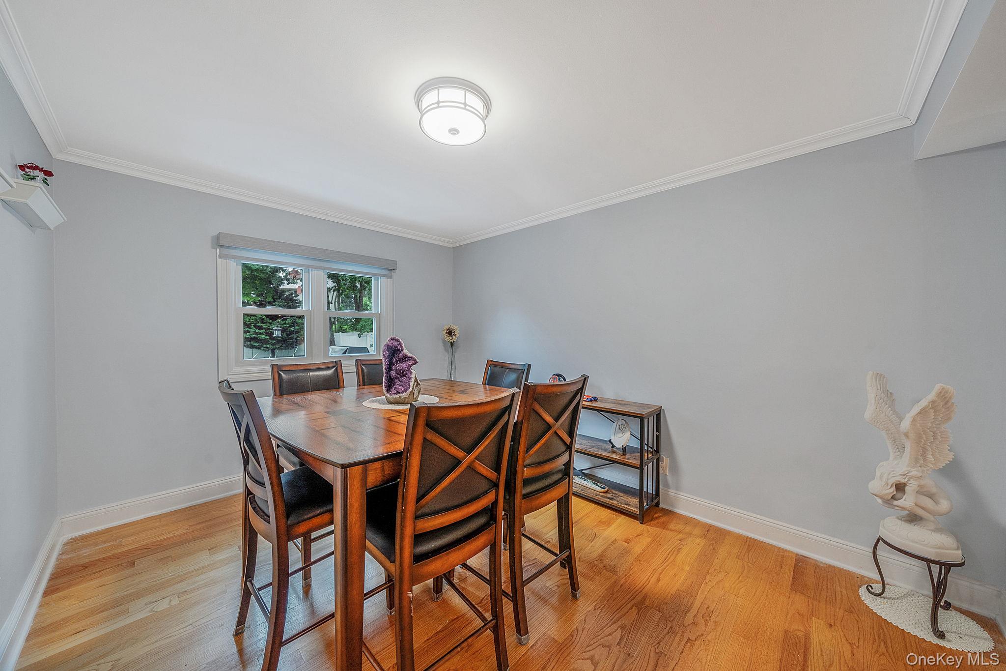 5 Rockhill Road Rocky Point, NY 11778 - Photo 14 of 48 Light-filled ding room featuring hardwood flooring, crown molding, a window with a roller shade, and a flush-mount ceiling light fixture