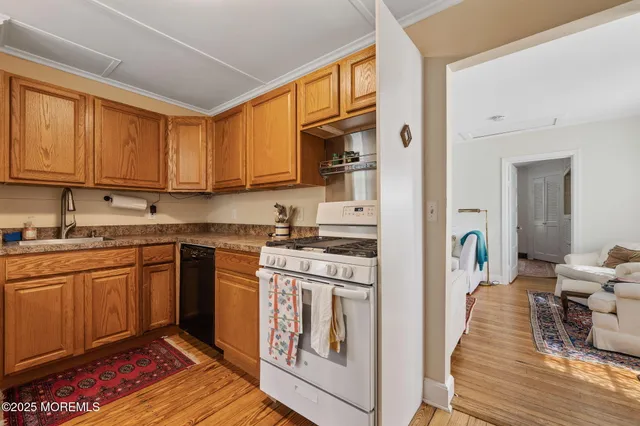 a kitchen with stainless steel appliances granite countertop a refrigerator a stove and white cabinets with wooden floor