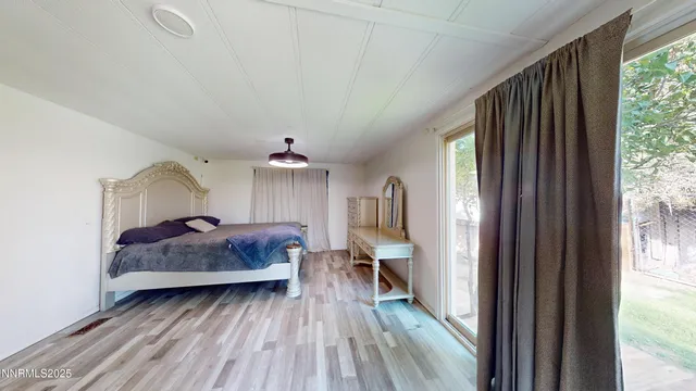 a spacious bedroom with a bed and wooden floor