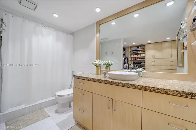 a bathroom with a granite countertop sink a toilet and a mirror