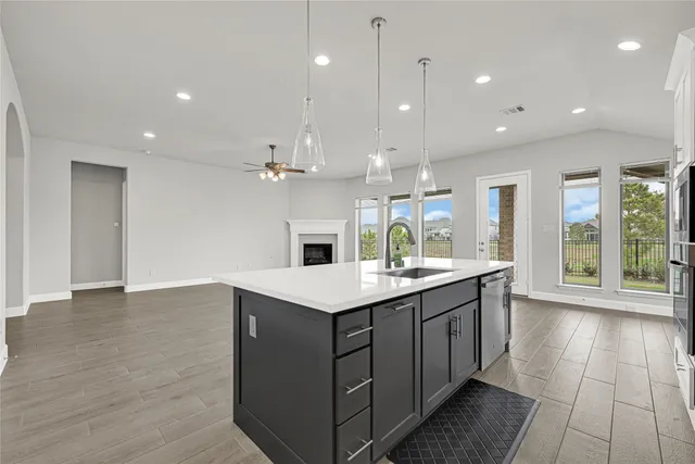 a open kitchen with kitchen island a sink dishwasher a stove and a refrigerator with wooden floor