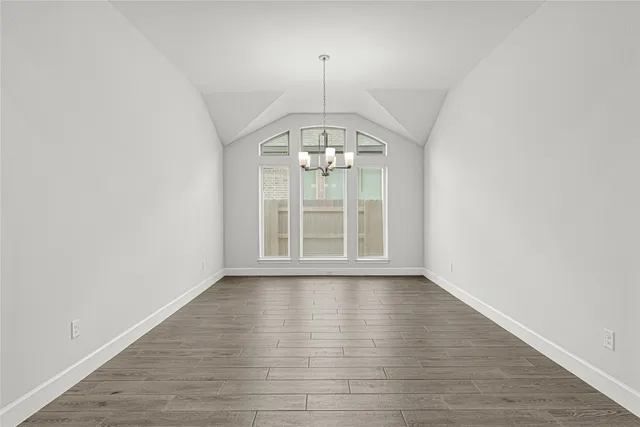 an empty room with wooden floor chandelier and window