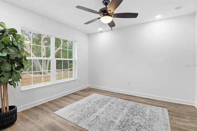 an empty room with windows and ceiling fan