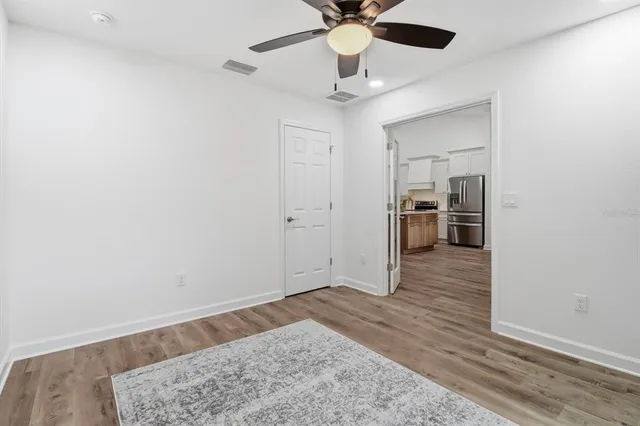 an empty room with wooden floor and a ceiling fan