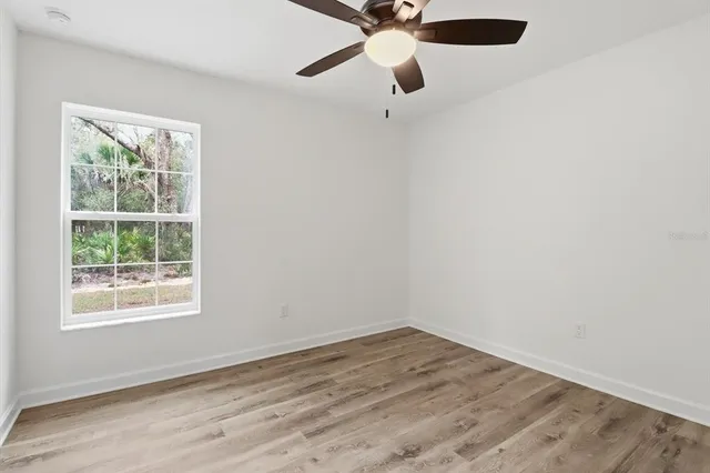 an empty room with a window and a ceiling fan