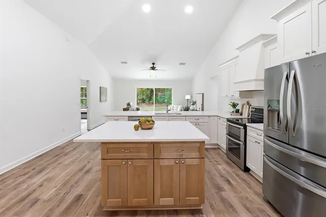 a kitchen with kitchen island granite countertop a sink cabinets and stainless steel appliances