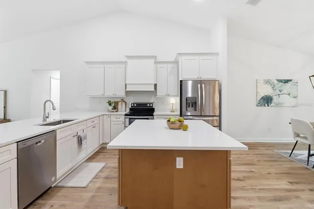 a kitchen with kitchen island a counter top space a sink stainless steel appliances and cabinets
