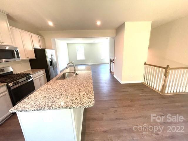 2052 Dornoch Road, Unit 1021C Tega Cay, SC 29708 - Photo 4 of 10 a kitchen with stainless steel appliances kitchen island granite countertop a refrigerator stove oven with white cabinets and wooden floor