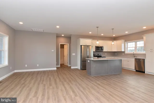 a large kitchen with stainless steel appliances a large counter top a refrigerator a sink and a stove