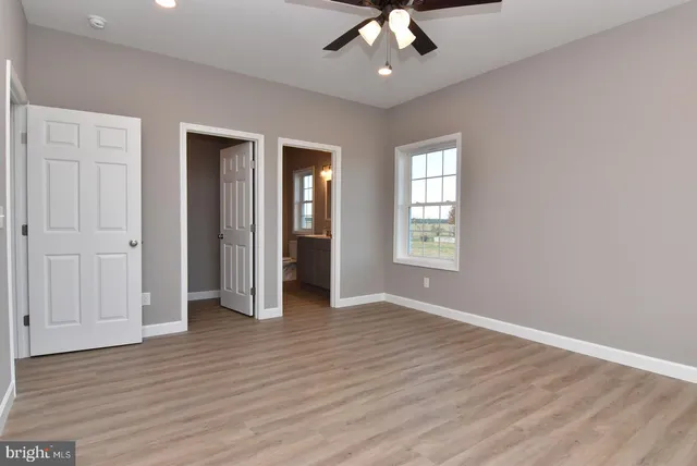 an empty room with wooden floor chandelier and windows