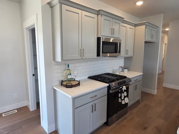a kitchen with stainless steel appliances a sink dishwasher stove and microwave with wooden floor
