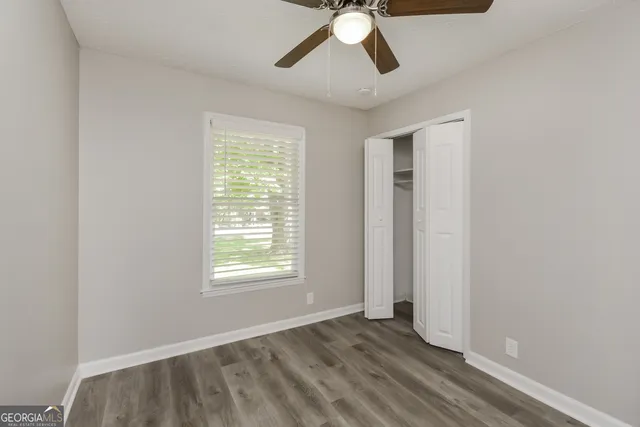 an empty room with a window and ceiling fan