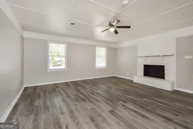 an empty room with windows fireplace and a sink