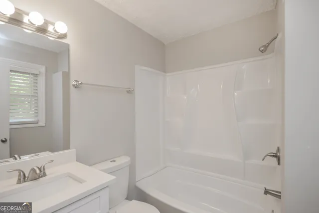 a white bath tub sitting next to a white sink and vanity