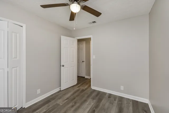 an empty room with wooden floor and fan