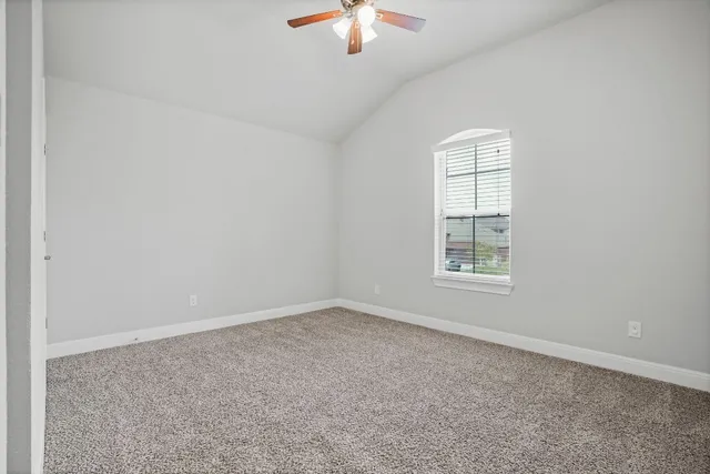 an empty room with a chandelier fan and windows