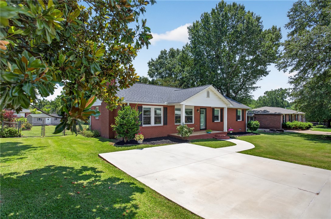 113 Greenfield Avenue Pendleton, SC 29670 - Photo 25 of 40 A classic brick exterior with a welcoming porch and a long, curving driveway leading to a well-maintained lawn.