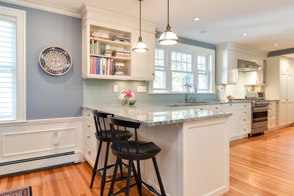 15 Selden Street Newton, MA 02468 - Photo 11 of 33 a kitchen with stainless steel appliances granite countertop a stove top oven a sink a dining table and chairs with wooden floor